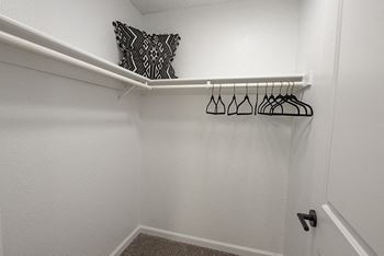 a walk in closet with a white rail and a black and white pillow